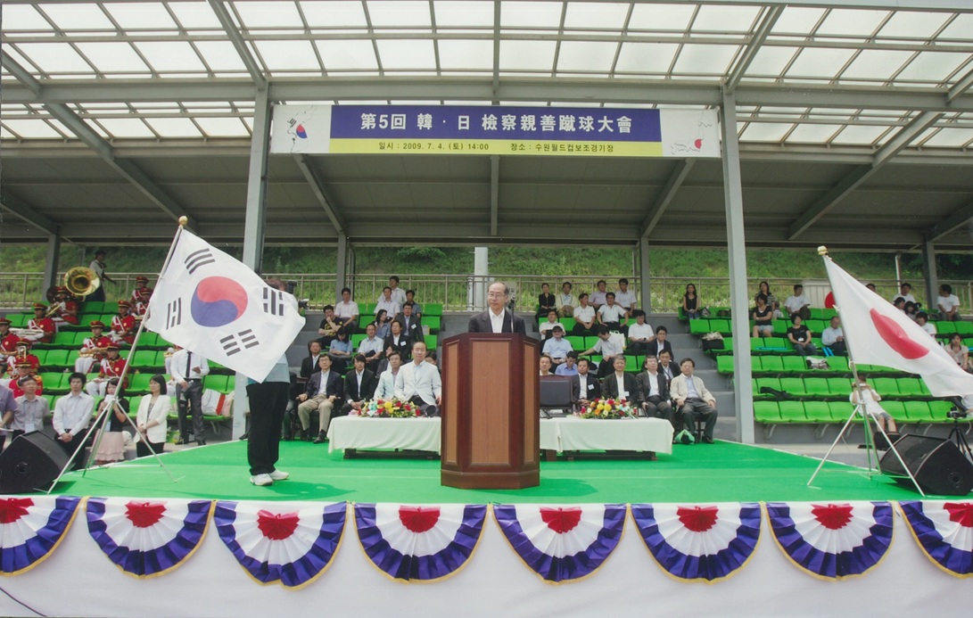 演説台に男性が立っている。頭上には「第五回」と記載のある幕が掲げられている。
